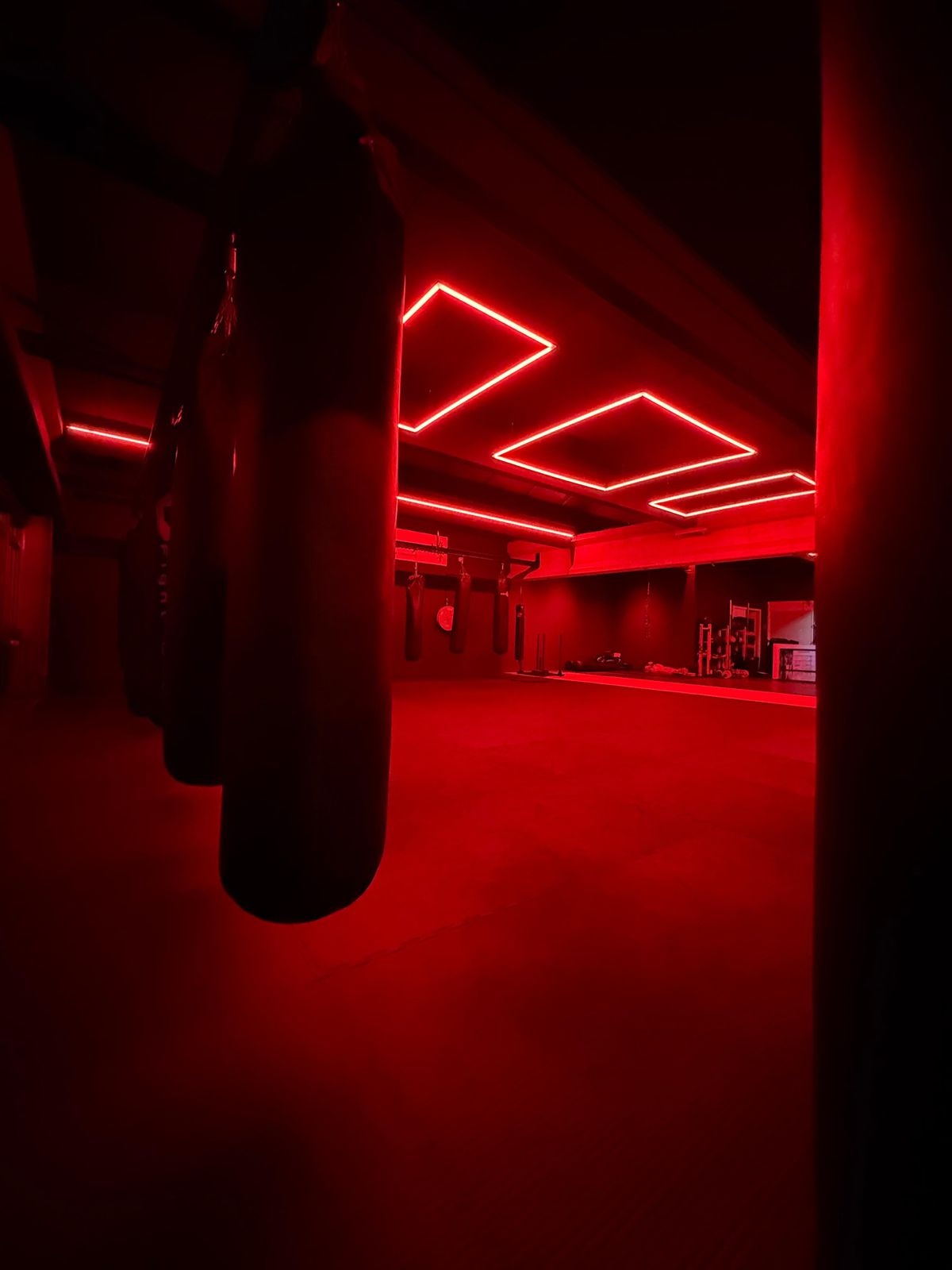 Sportschoolruimte met rode LED-verlichting en bokszakken. voor Power Up Gym Assen