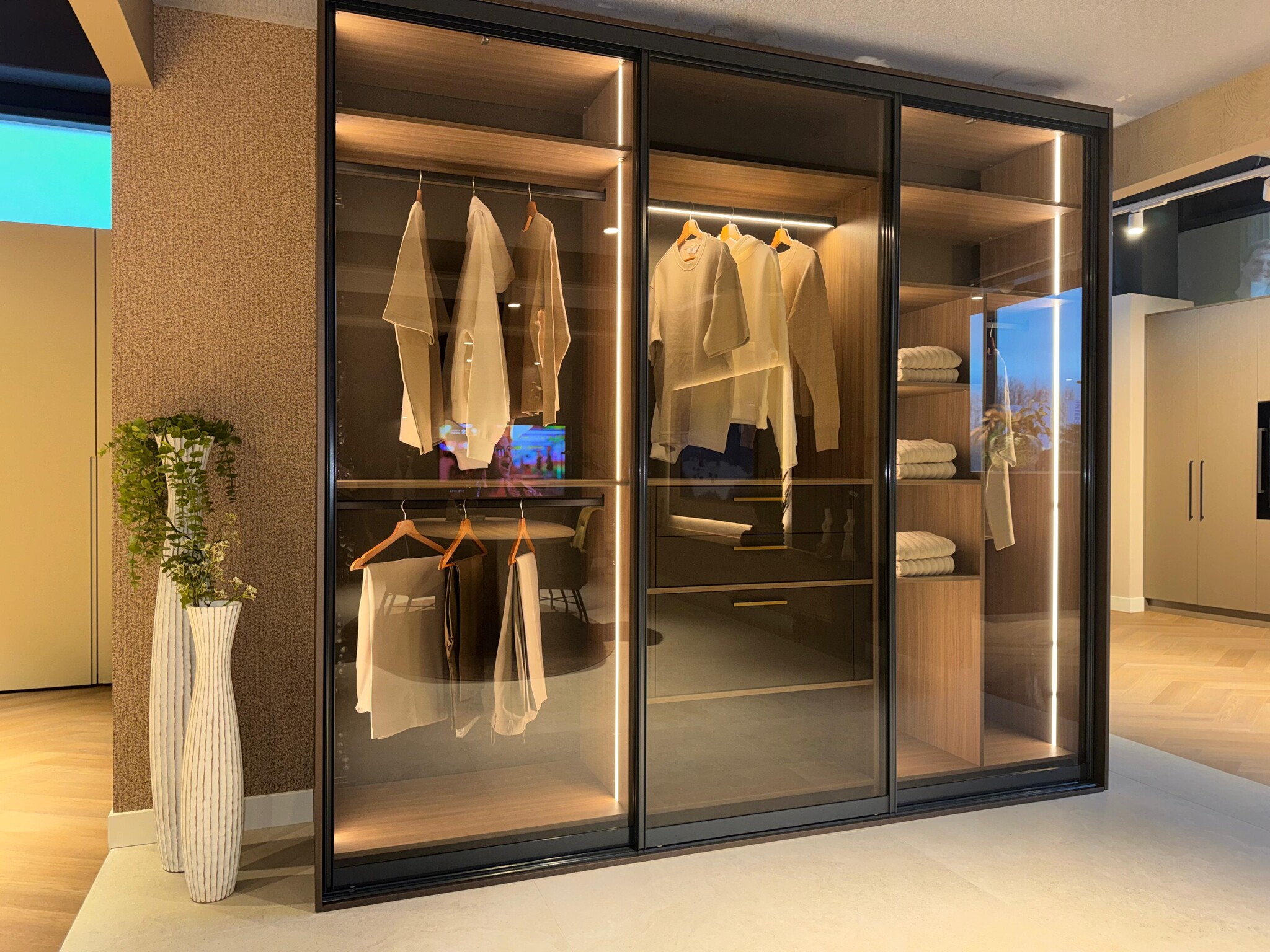 Moderne inloopkast met glazen schuifdeuren en LED-verlichting in een showroom. in Woninginrichting aan huis Zaanstad