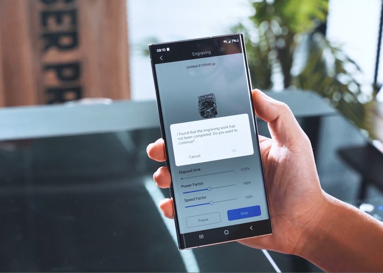 Hand holding a mobile phone showing a dialog warning that egraving has been interrupted and if asking if they want to continue.