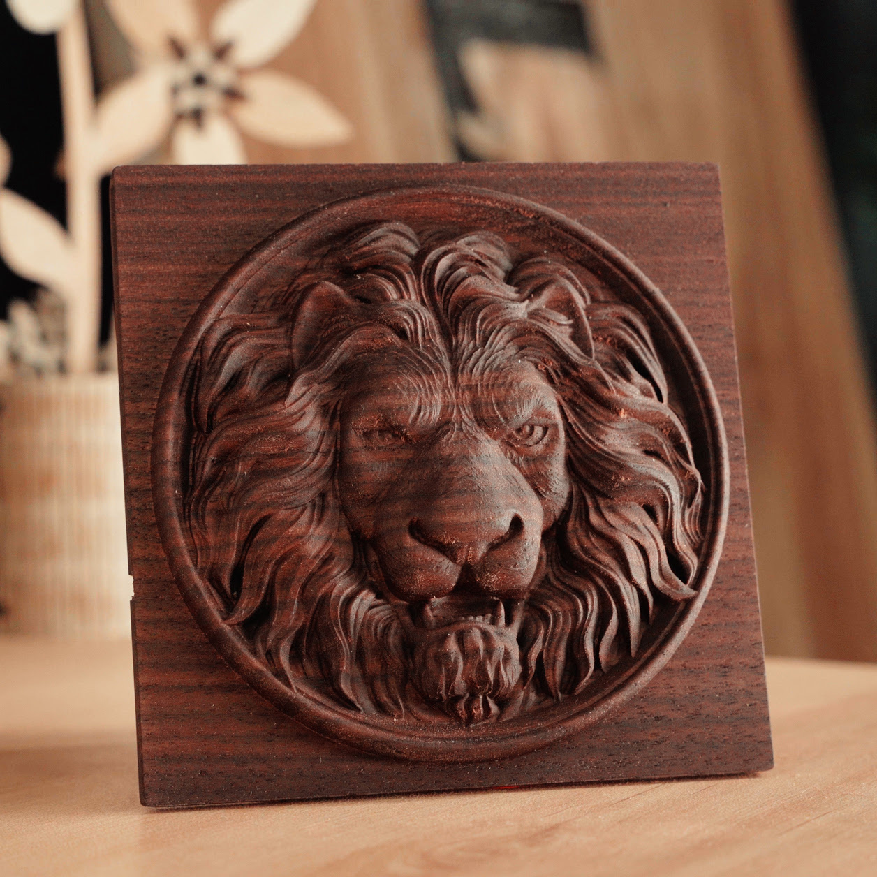 Square piece of black walnut wood with a circular milled design of a lion s head