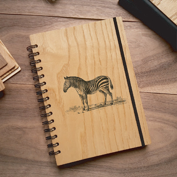 Notebook with a wooden cover and an engraved zebra on the front.