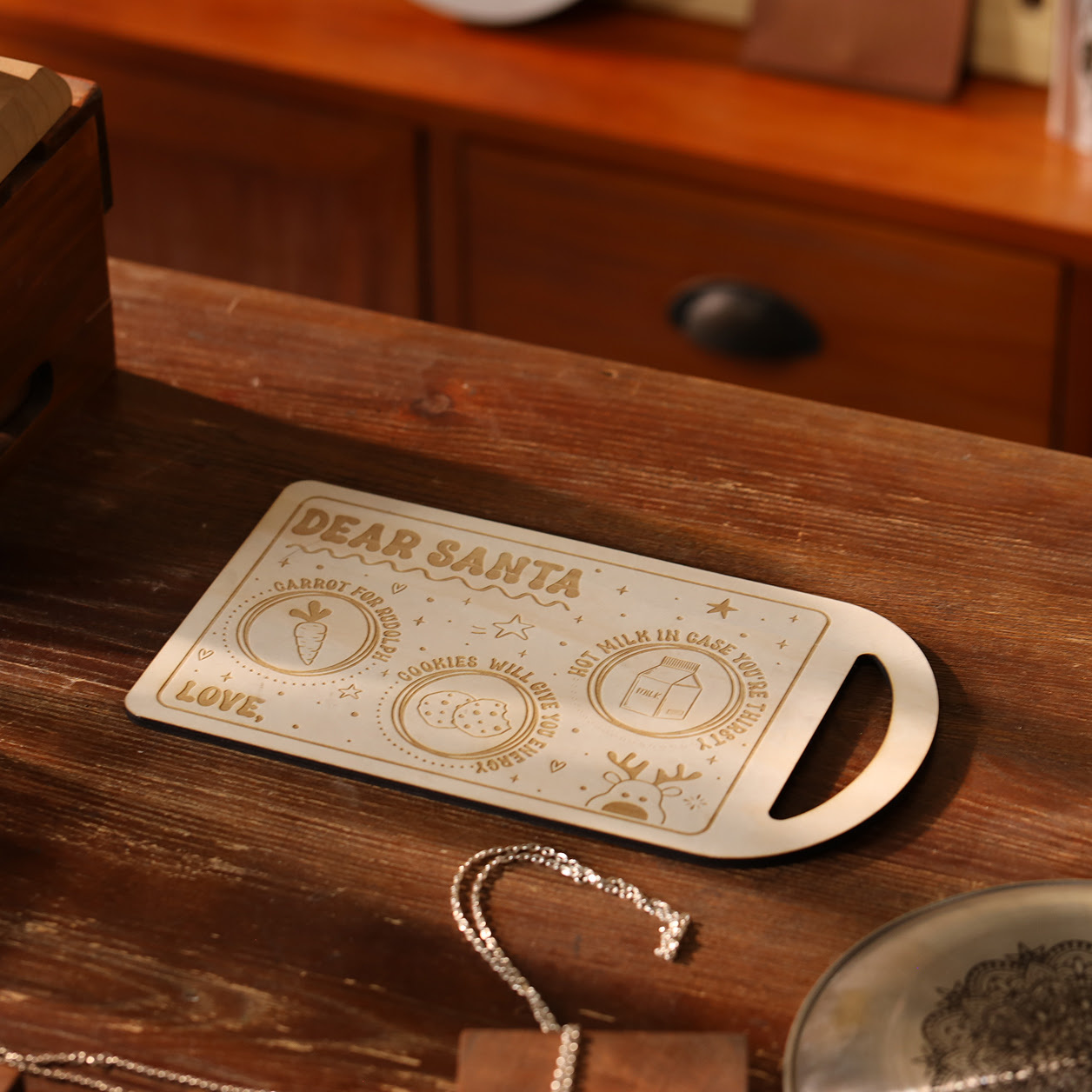 Wooden cutting board with an engraved design of the text Dear santa and spots to put a carrot, cookies and milk.