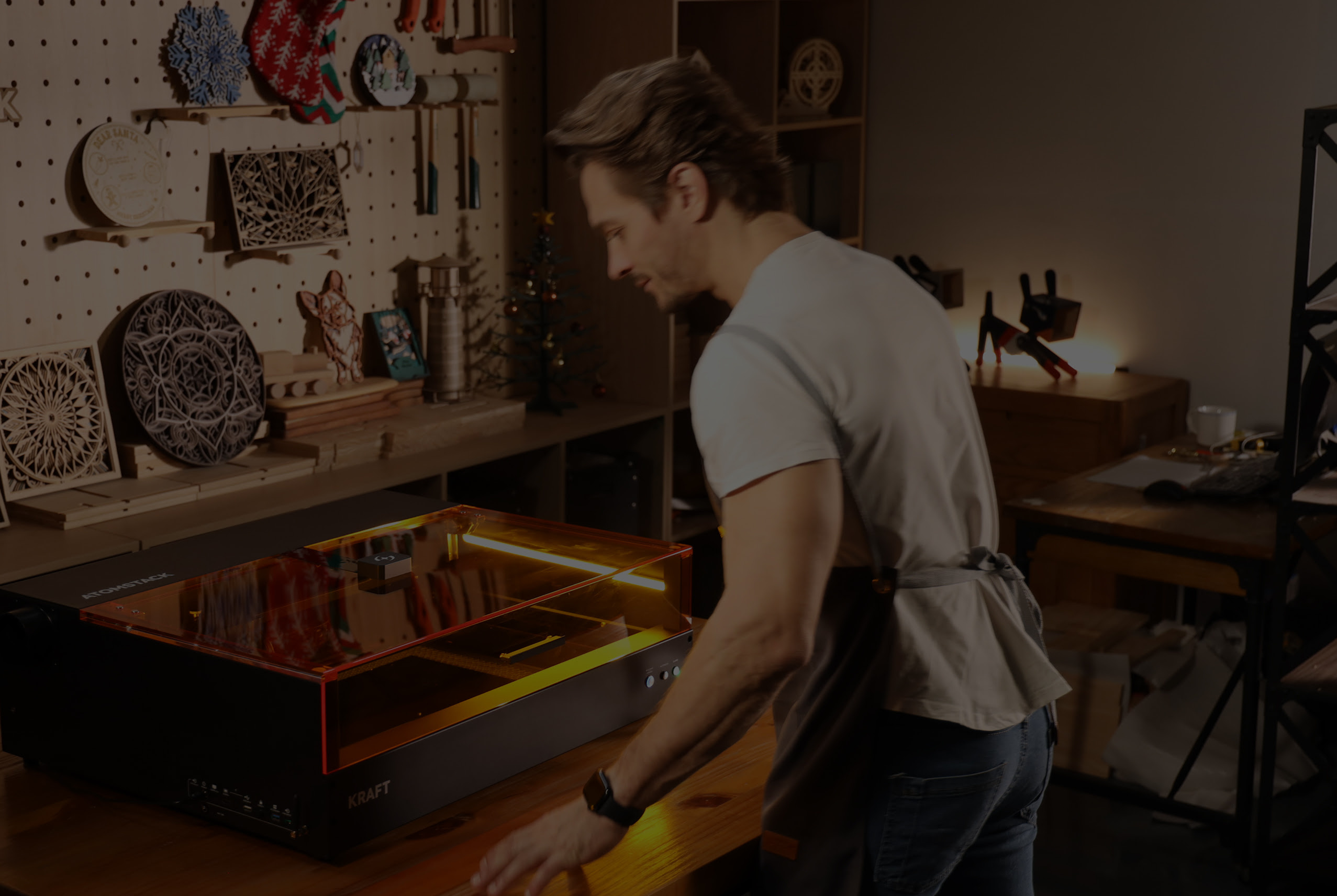 Man in a workshop looking at what is happening inside of the AtomStack Kraft 40 W.