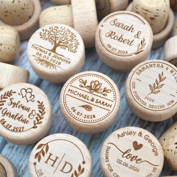 Collection of custom-engraved cork wine bottle stoppers with personalised wedding names and dates.