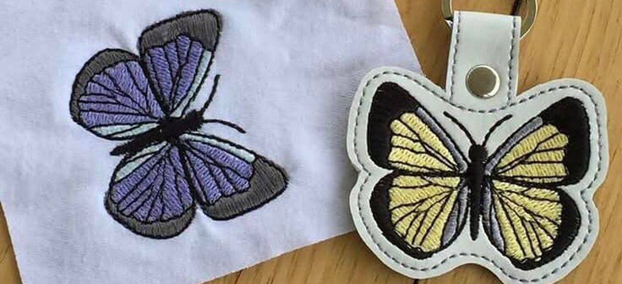 Dos mariposas bordadas. Una en tela y la otra en una etiqueta de cuero.
