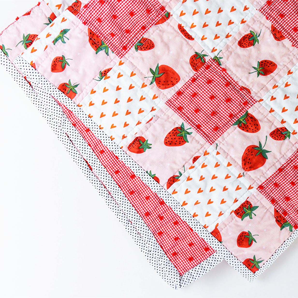 Patchwork blanket made of pink and strawberry fabric.