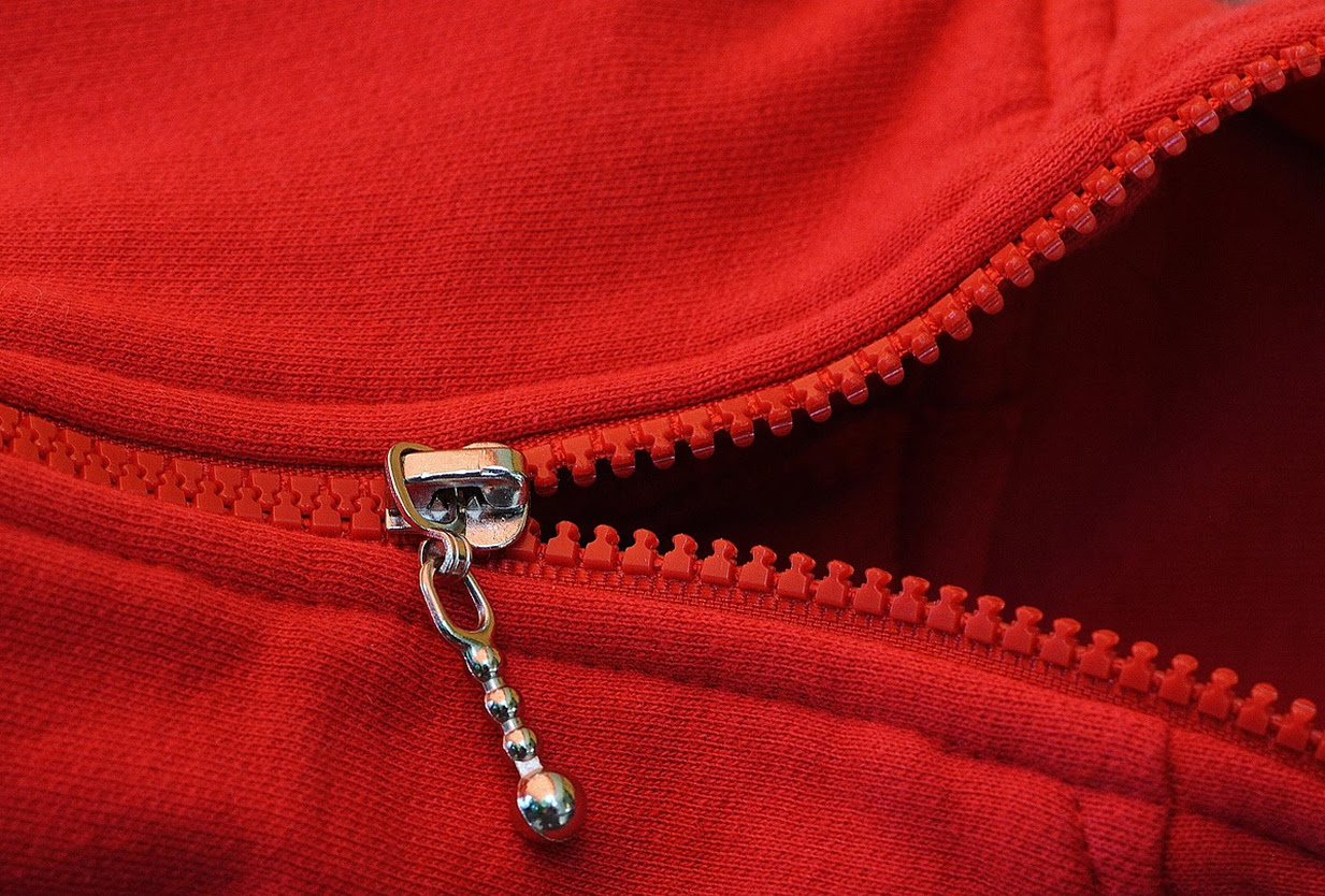 Close-up of a zipper on a red sweater vest.