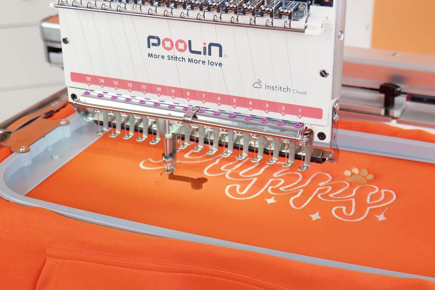 PooLin EOM embroidering the text Puppy on an orange sweater.