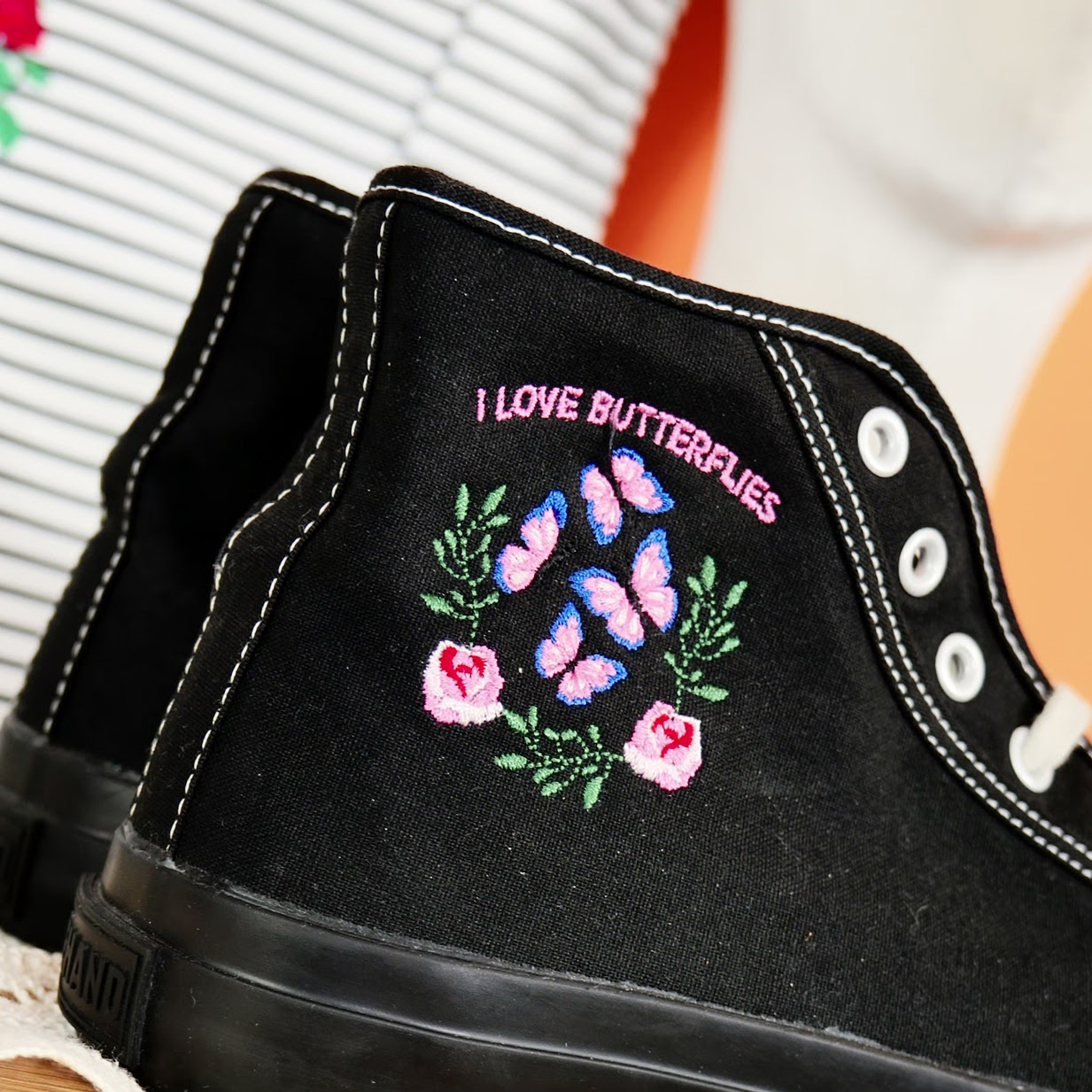 Black Converse shoes with an embroidered design of flowers and butterflies and the text: I love butterflies.