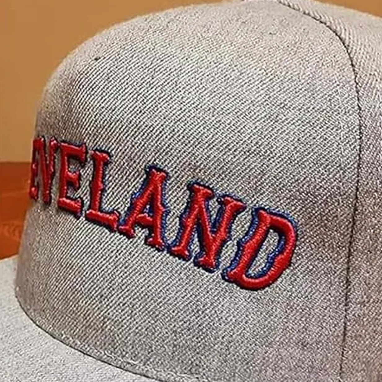 Close-up of a grey cap with an embroidered red text.