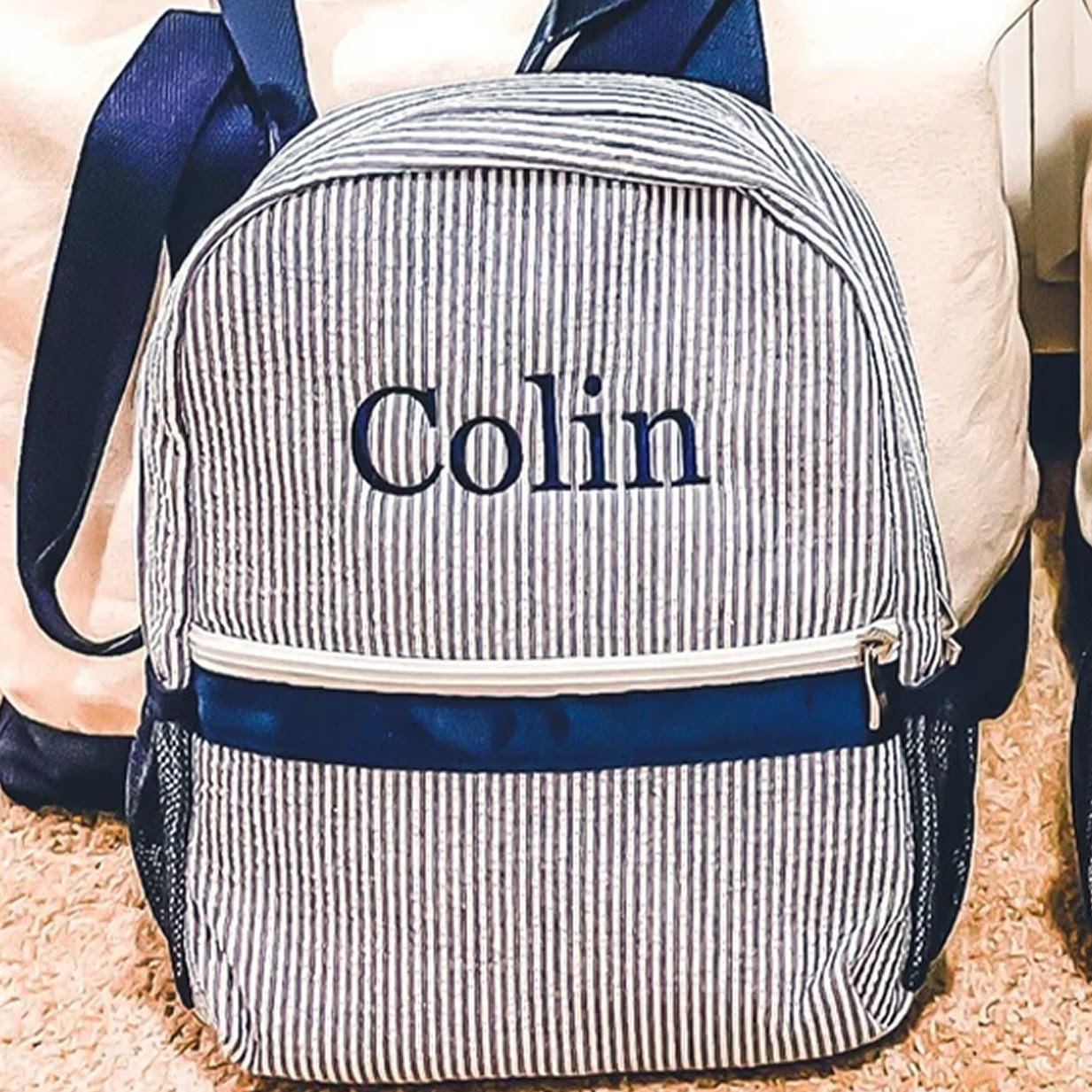 Children's blue striped backpack with the name Colin embroidered on it.