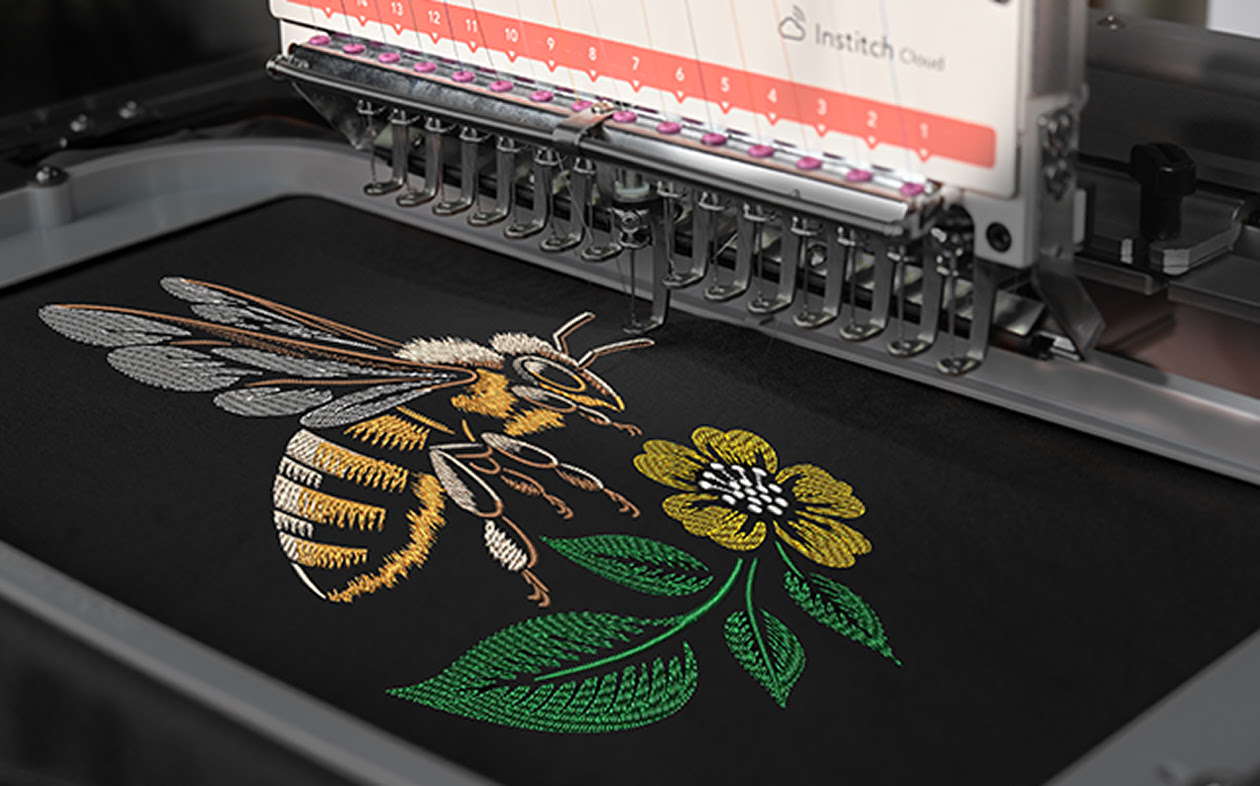 Embroidery hoop with an embroidered design of a honey bee on black fabric