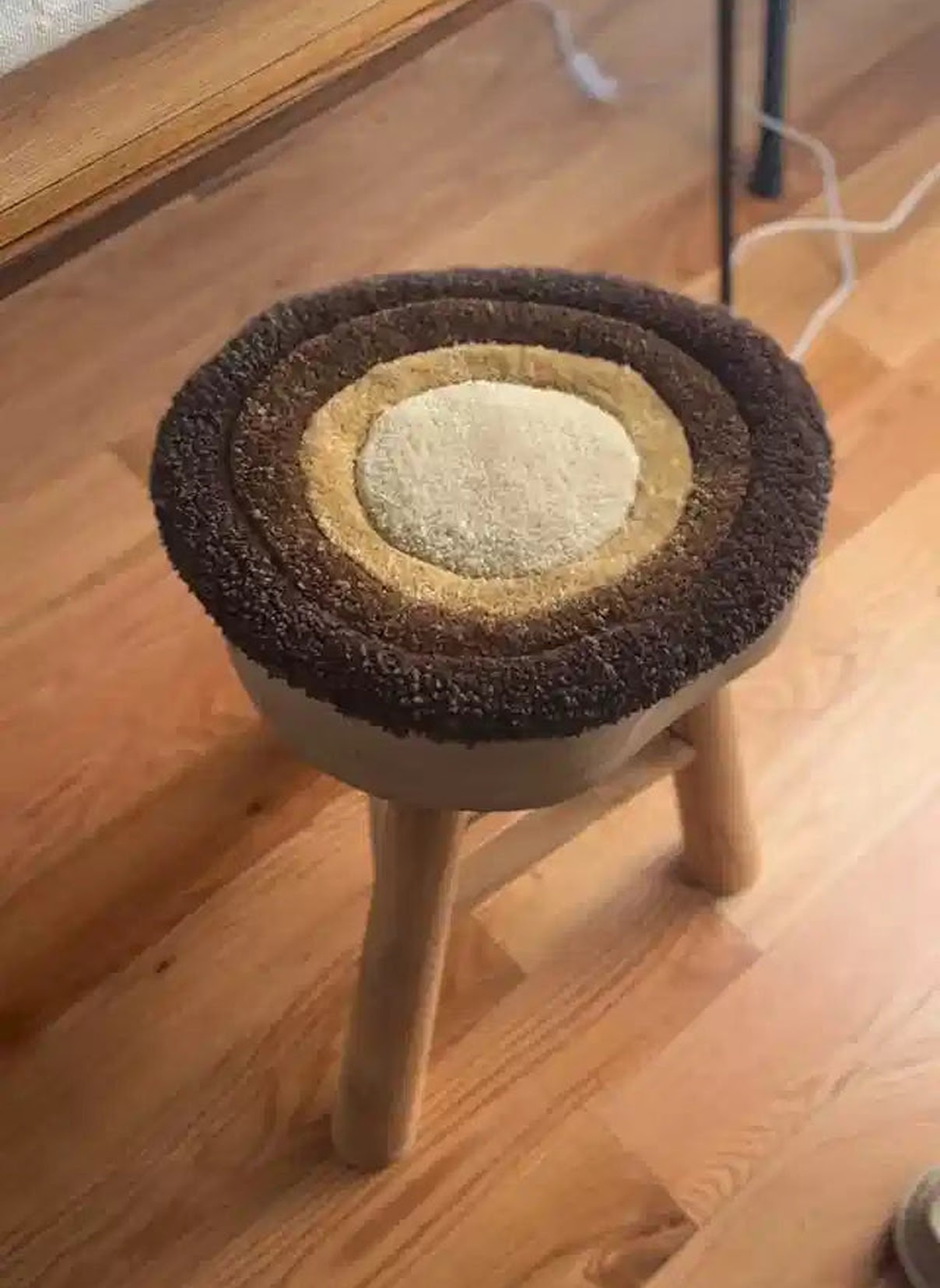 Stool with a tufted seat. The design are concentric circles in different shades of brown.