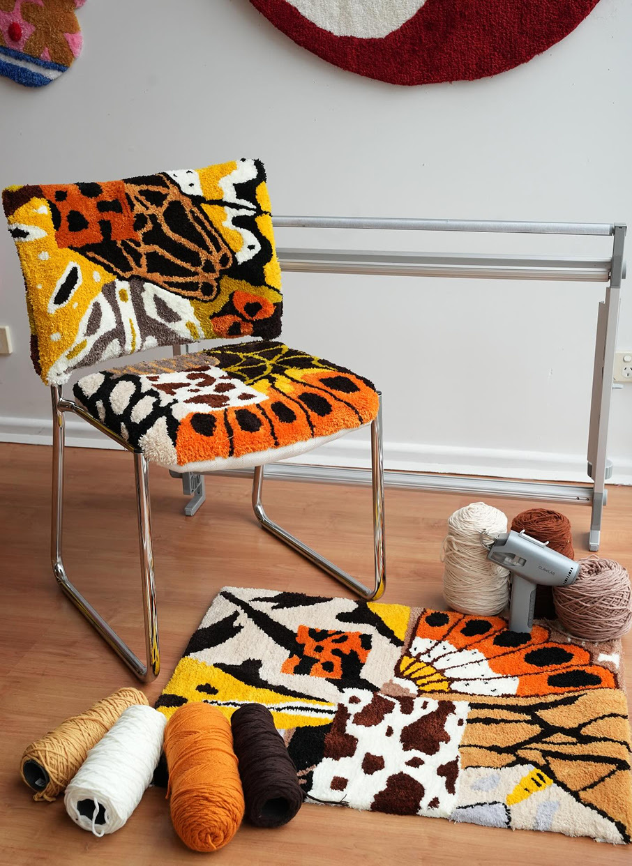Chair with a tufted seat and back in orange, brow, black, red and white yarn.