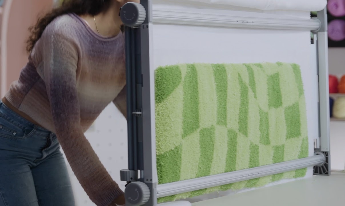 Woman pulling part of a checkered green tufted rug down on the Clawlab Tufting Frame H1.