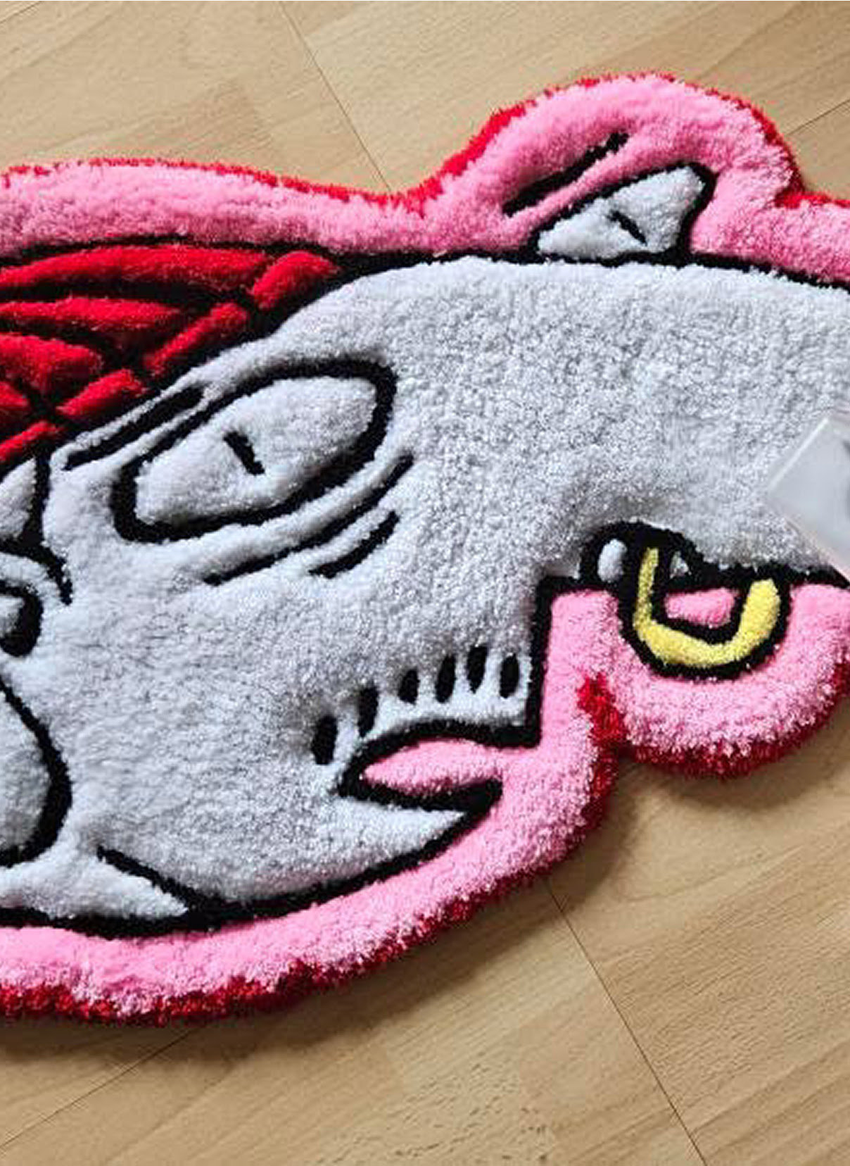 Tufted rug of a cartoon head of a guy in a red beanie with a nose ring.