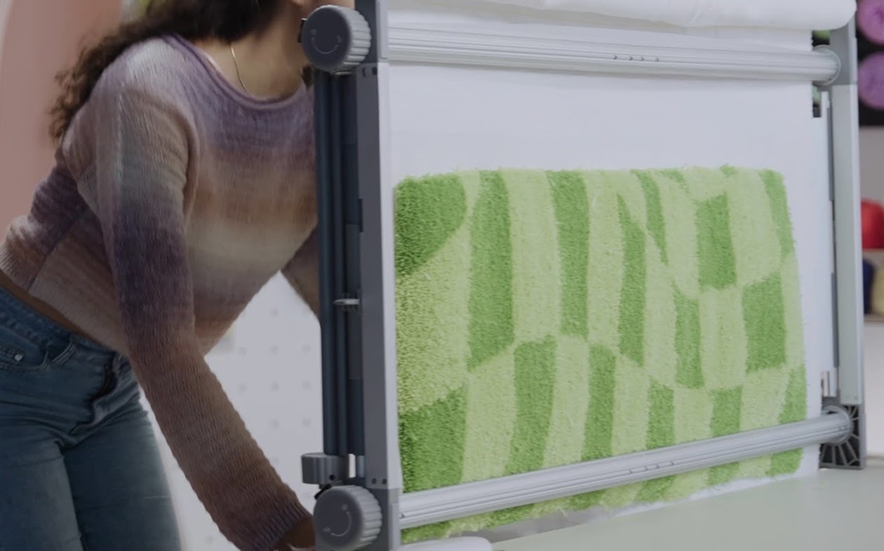 Woman pulling part of a checkered green tufted rug down on the Clawlab Tufting Frame H1.