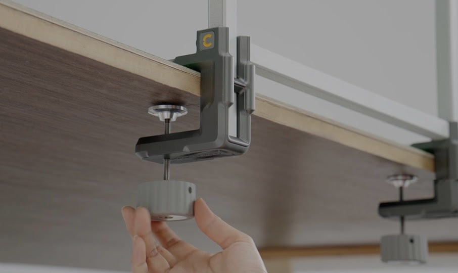 Hand tightening the clamp of the tufting frame to secure it to a table.