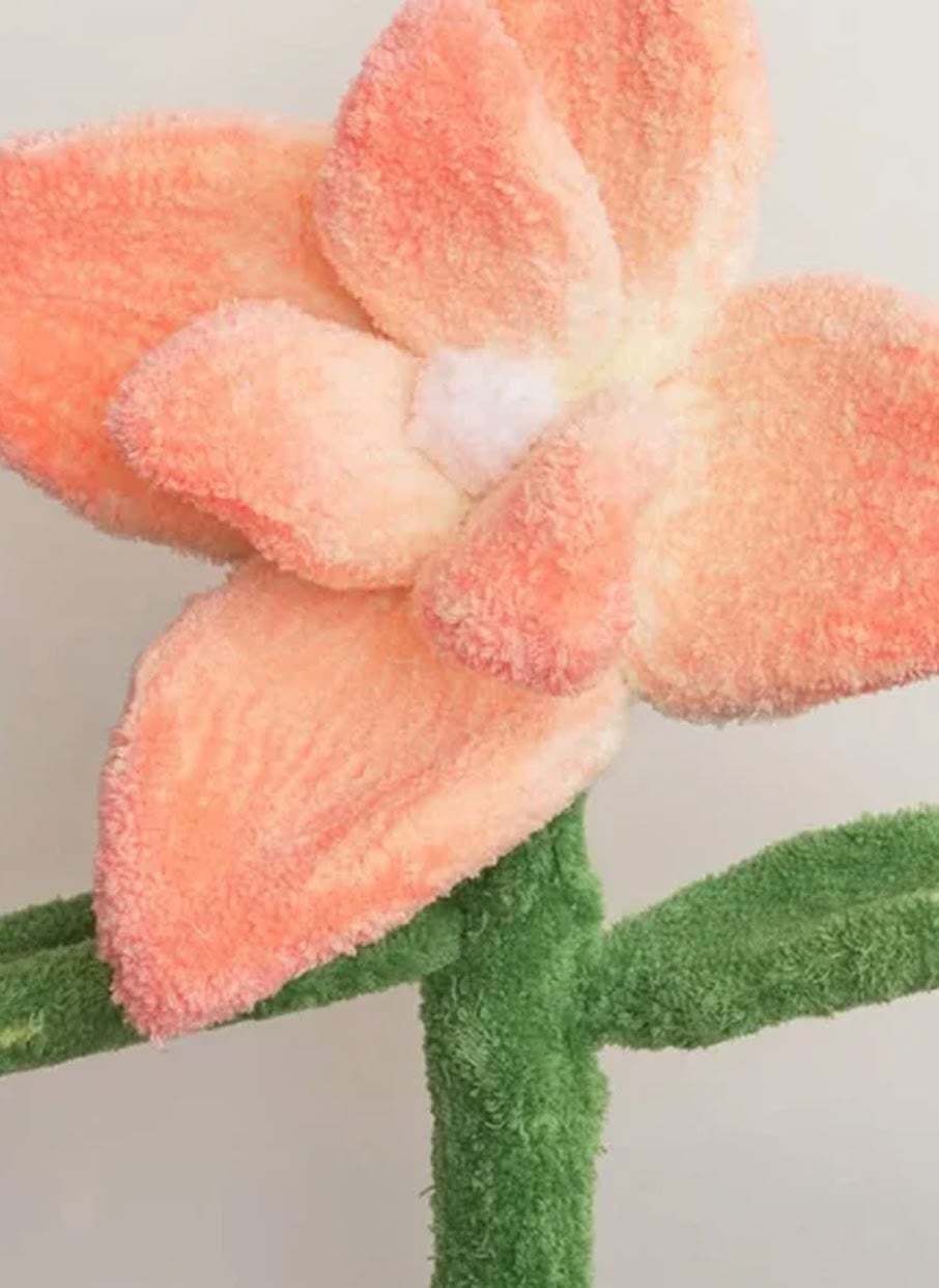 Close-up of a 3D tufted plush flower art piece with peach-colored petals and a green stem.