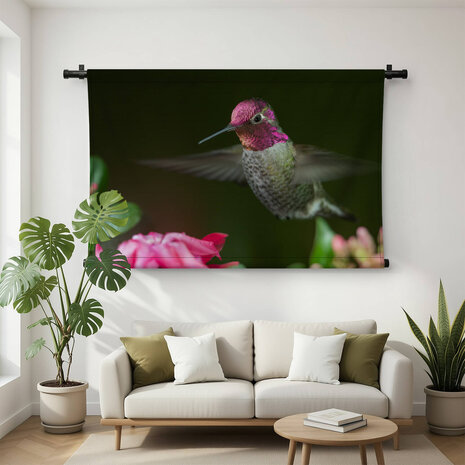 Kolibrie zwevend bij roze bloemen