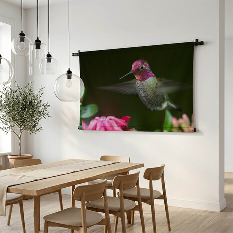 Kolibrie zwevend bij roze bloemen