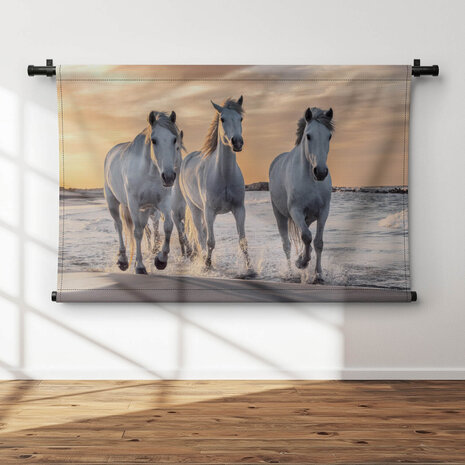 Kudde witte paarden op het strand