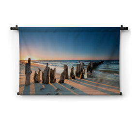 Zonsondergang op het strand en oude houten golfbrekers