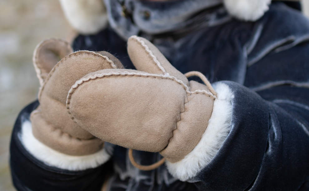 Lamsvacht babywantjes taupe Meisje draagt taupe kleurige lamsvacht babywantjes van Van Buren