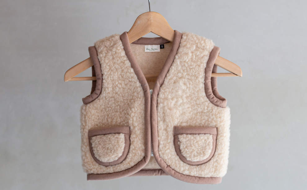 Beige wollen baby bodywarmer maat s op een kledinghanger