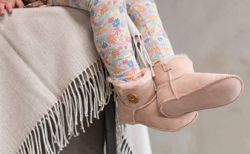 Meisje draagt roze baby slofjes maat 20/21 zittend op een barkruk