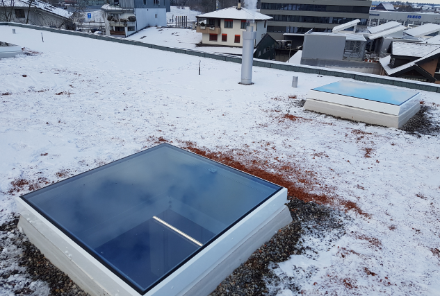 Twee vierkante platdakramen op een besneeuwd plat dak
