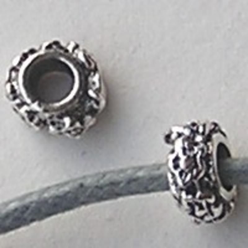 Metalen kraal met bloemetjes. Rondelle. Oudzilverkleurig. 3.5x6.5mm. Per stuk voor.