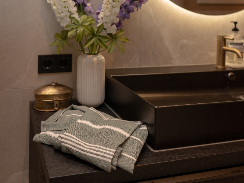 lichte badjas van hamamkatoen naast wasbak in moderne badkamer