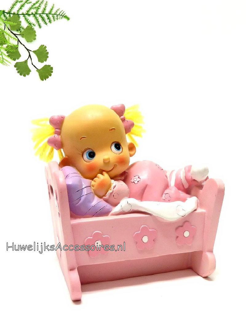 Leuke baby meisje ligt in haar bedje met een roze pyjama aan