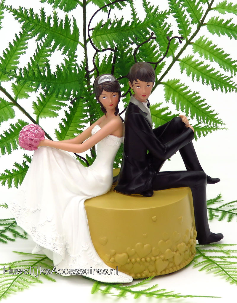 Bruidspaar zitten samen op een ronde poef taarttopper