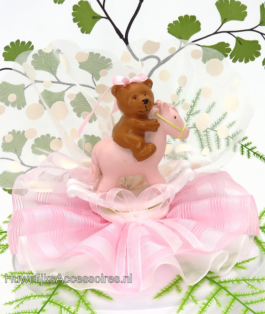 Baby beertje op een schommelpaard met roze kante voetstuk