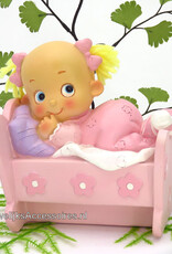 Leuke baby meisje ligt in haar bedje met een roze pyjama aan