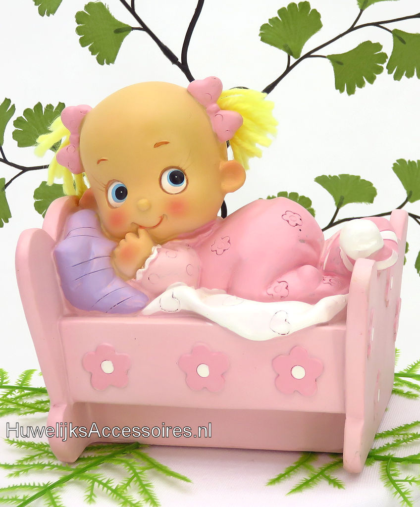 Leuke baby meisje ligt in haar bedje met een roze pyjama aan