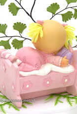 Leuke baby meisje ligt in haar bedje met een roze pyjama aan