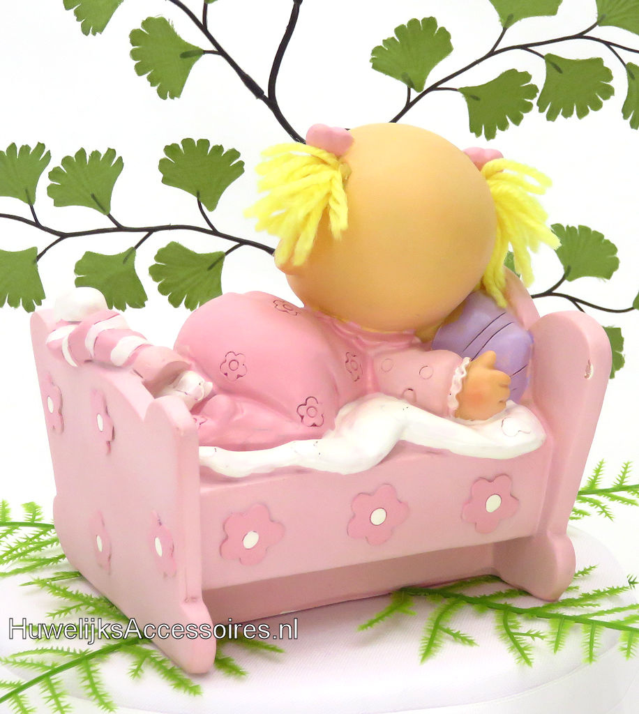 Leuke baby meisje ligt in haar bedje met een roze pyjama aan