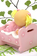 Leuke baby meisje ligt in haar bedje met een roze pyjama aan