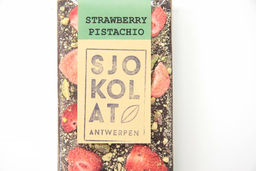 A dark chocolate bar with strawberries and pistachio nuts