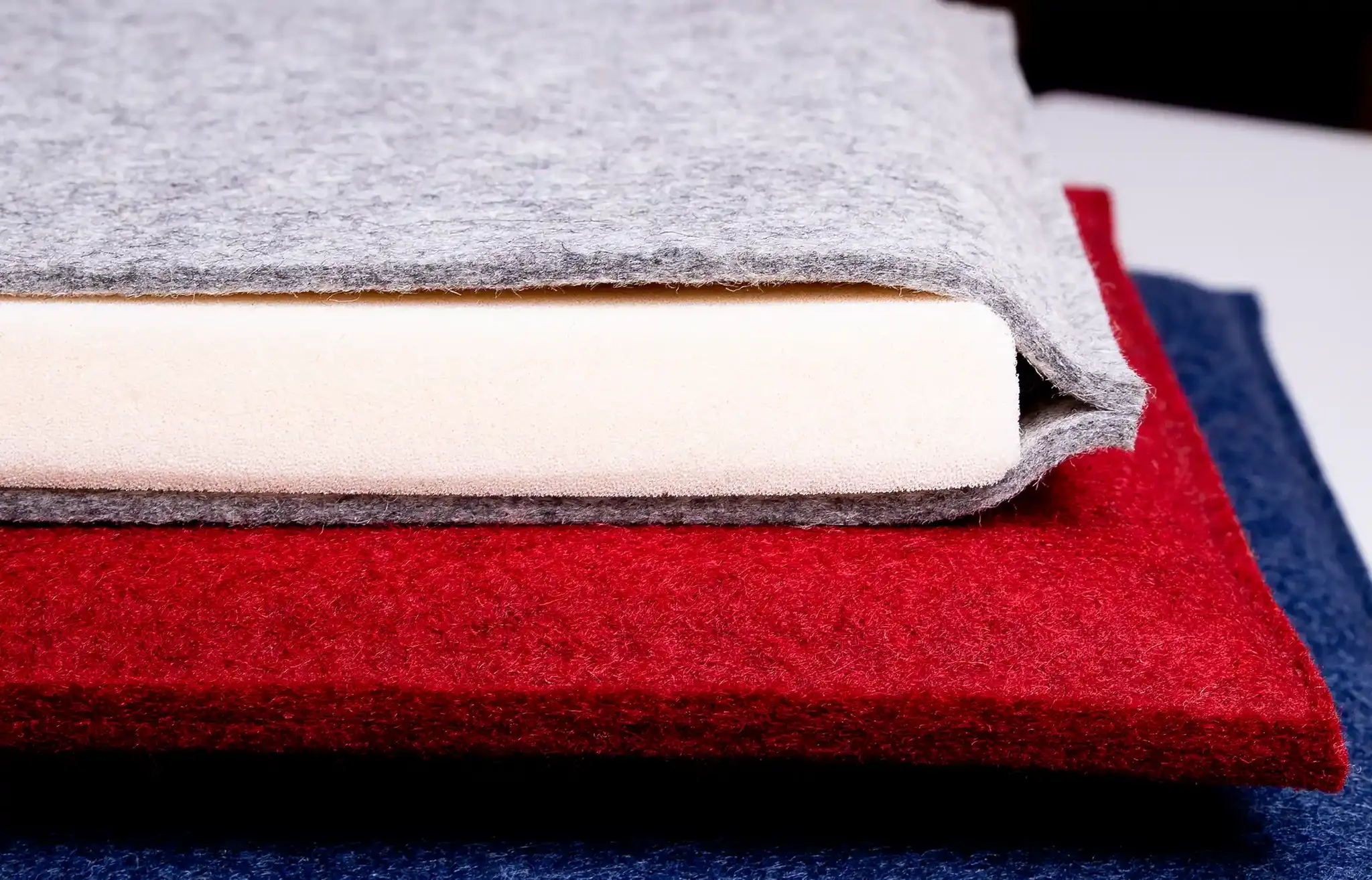 Opened seat cushion made of grey wool felt with a 20 mm RG 50/78 foam core, with red and blue felt cushions underneath